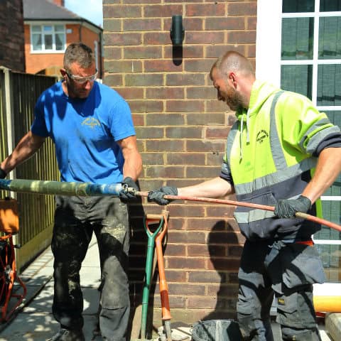 Two drainage experts from a local Warrington drain company working on a drain repair