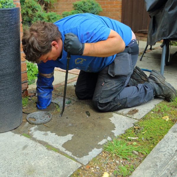 A drainage expert working on a blocked drain in Warrington