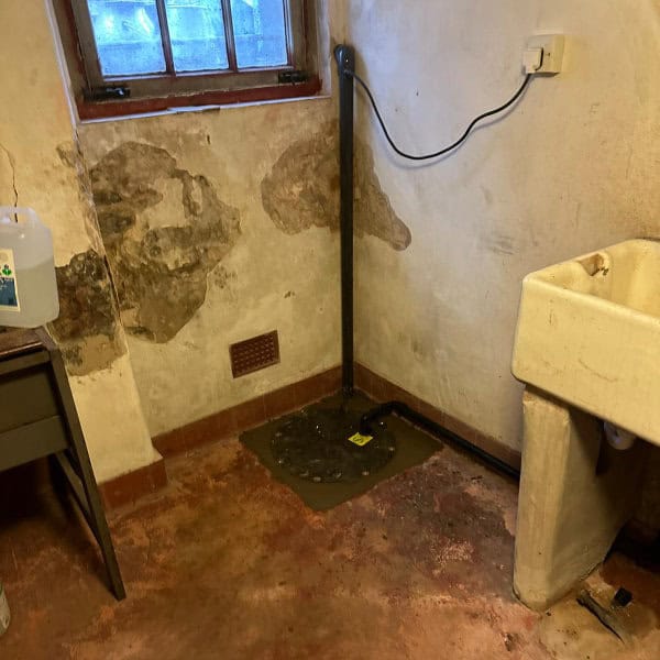 A completed sump pump installation in a basement room in Warrington next to an old sink